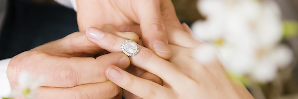 a man putting on an engagement ring on his fiancee